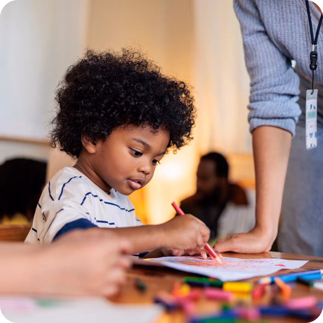 A young boy concentrating on coloring with crayons