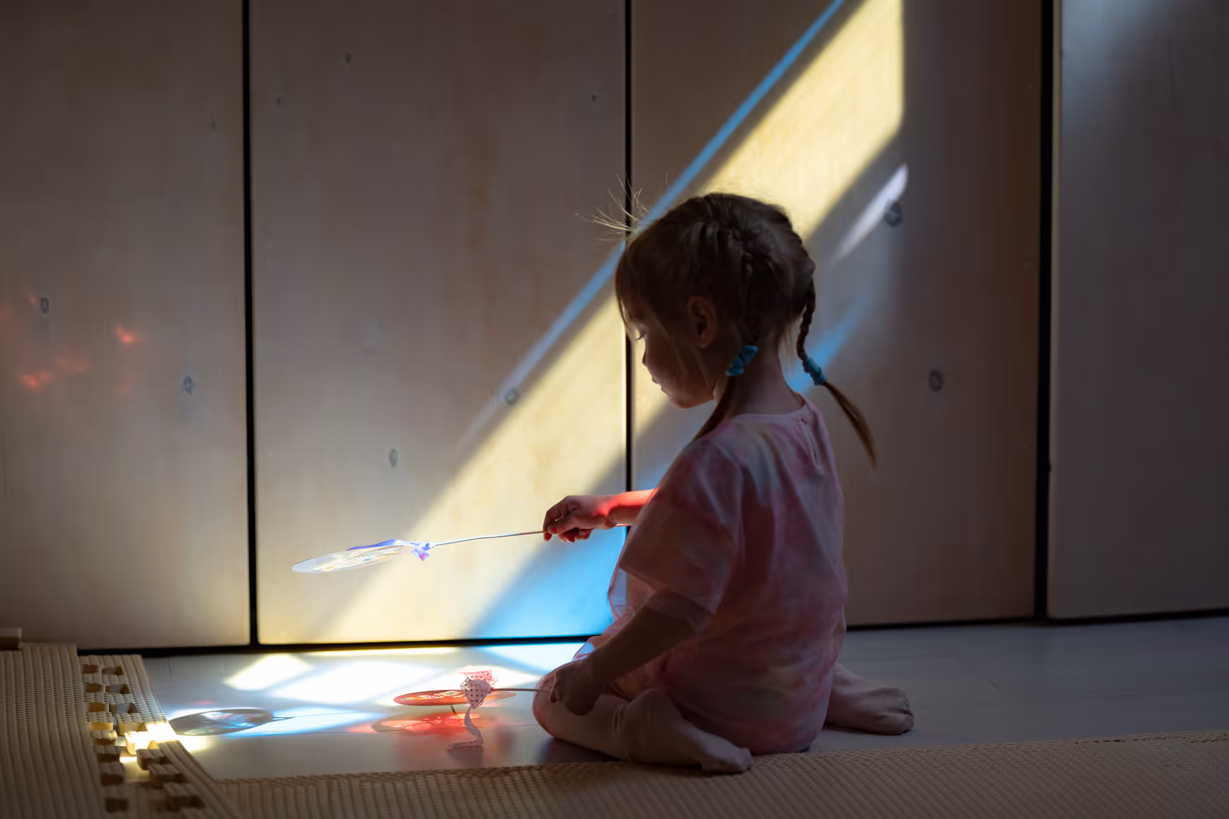 A young child playing quietly in a beam of sunlight