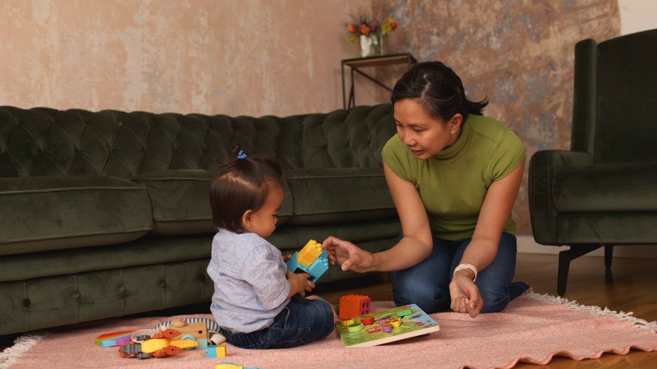 An Origin physical therapist playing with a toddler on the living-room floor
